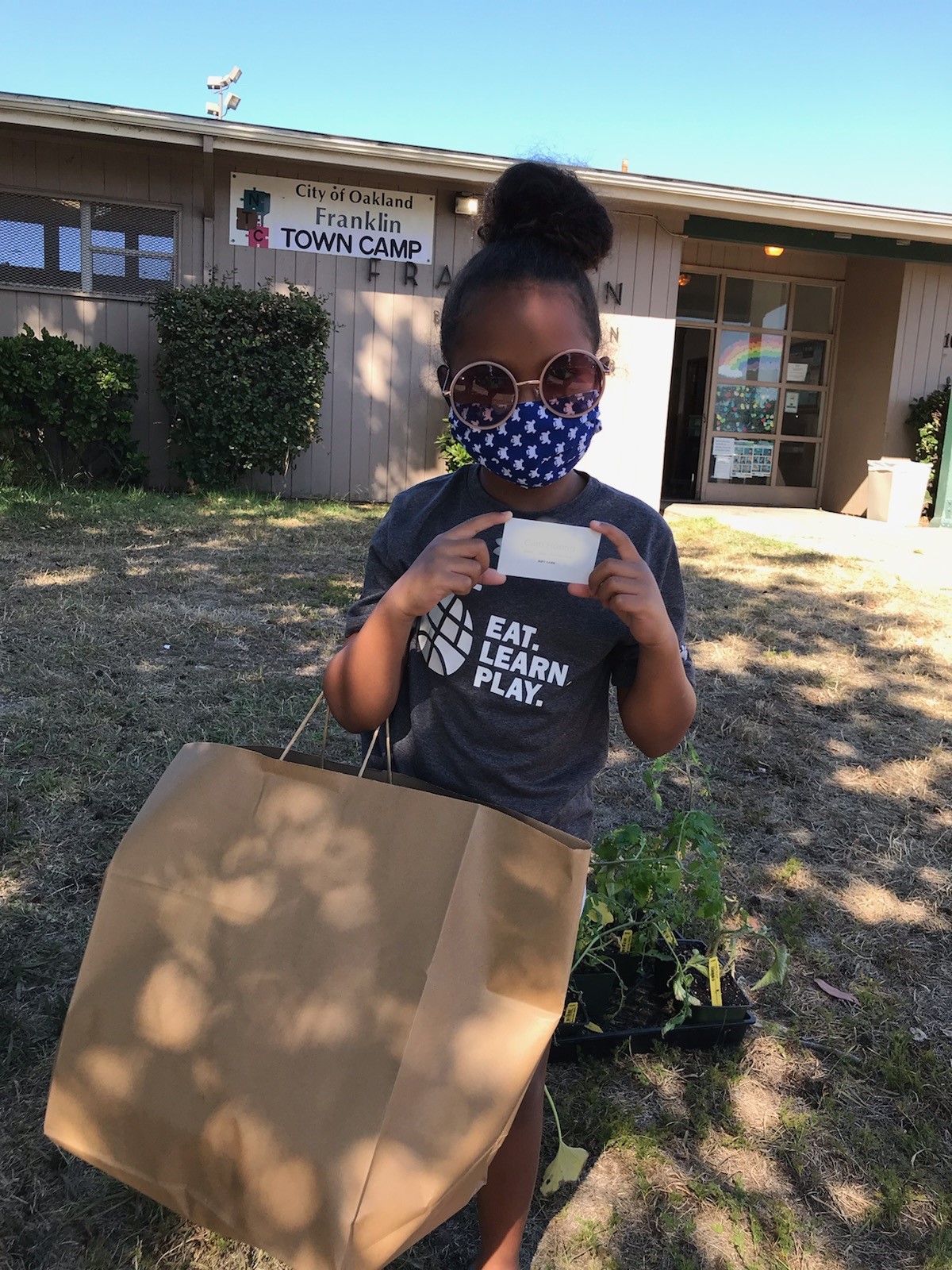 A Town Camp attendee at the Franklin Center holds a bag of meals from Kitchens Around the World to share with her family. Photo courtesy Oakland Parks, Recreation & Youth Development