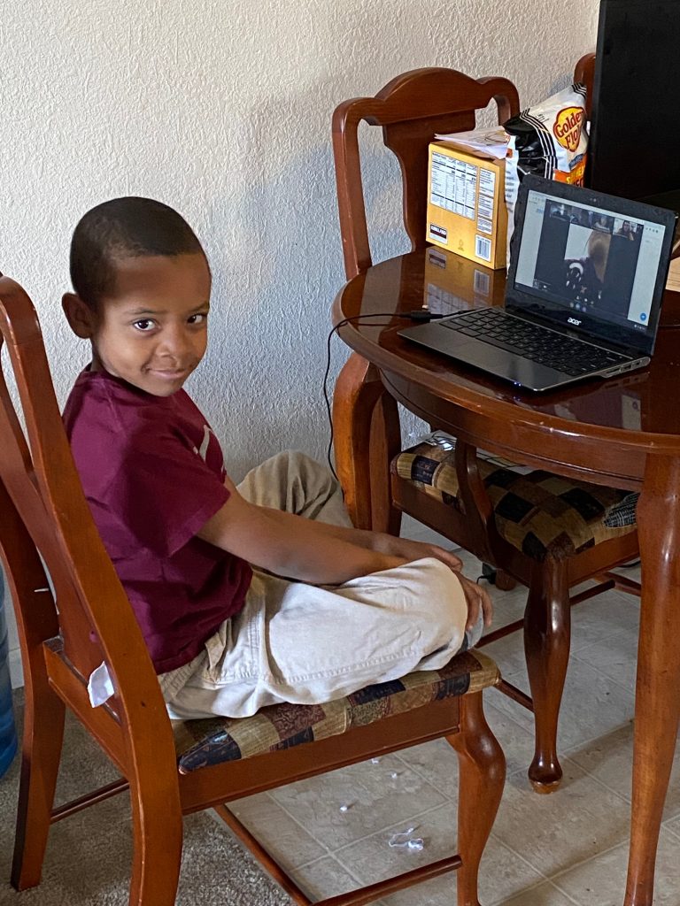boy sitting at table in front of computer