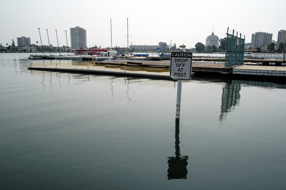 Boat docks at Lake Merritt. A sign portruding from the water cautions people that there's a "steep drop off" beneath the surface.