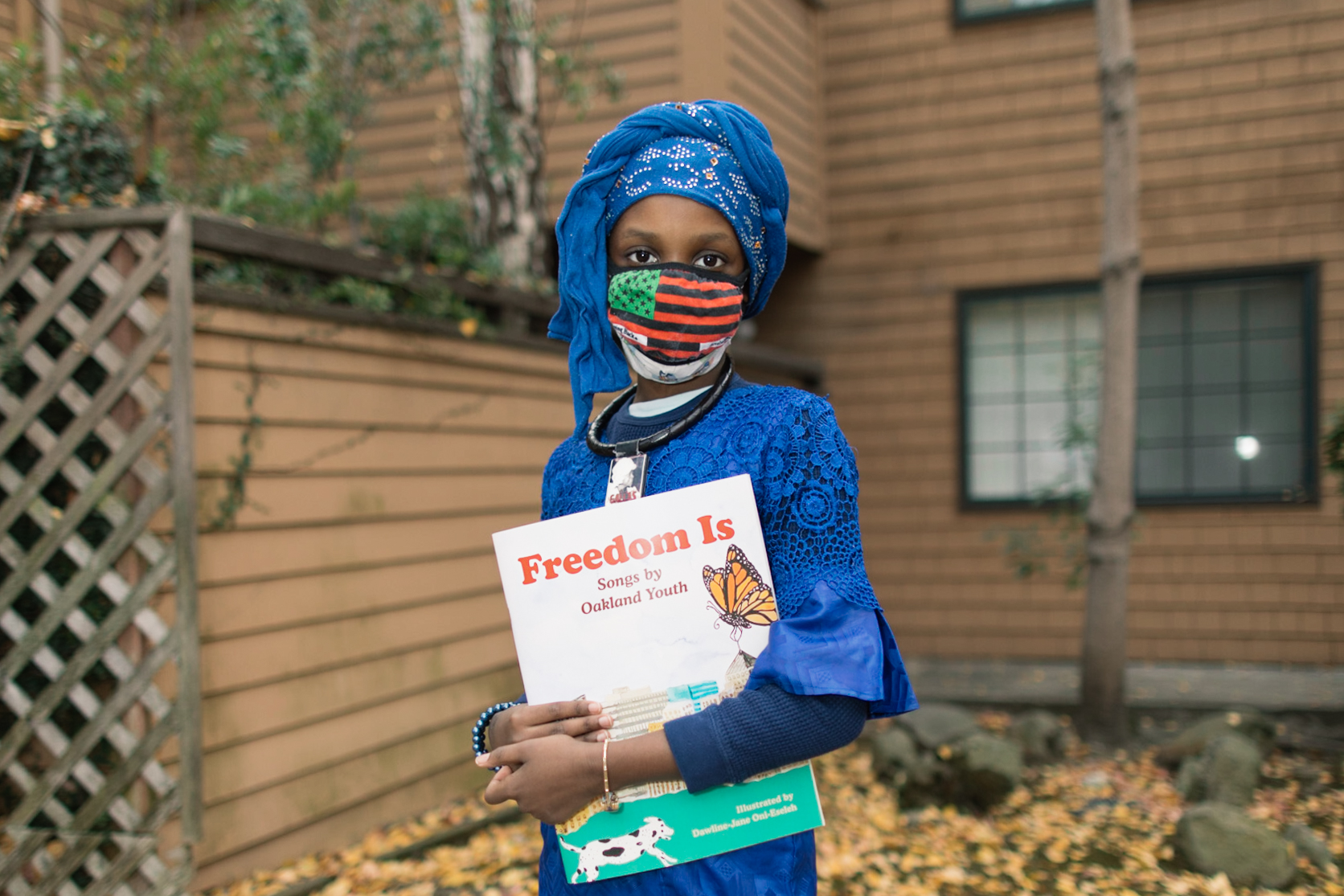 A youth writer named Nafissatou Ndiaye holding a copy of "Freedom Is," a companion book to a musical album of the same name, produced by the nonprofit Chapter 510