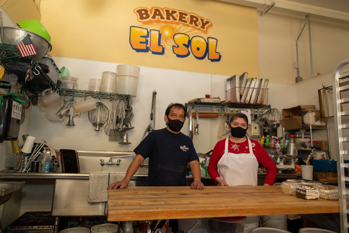Owners of Bakery El Sol in front of signage
