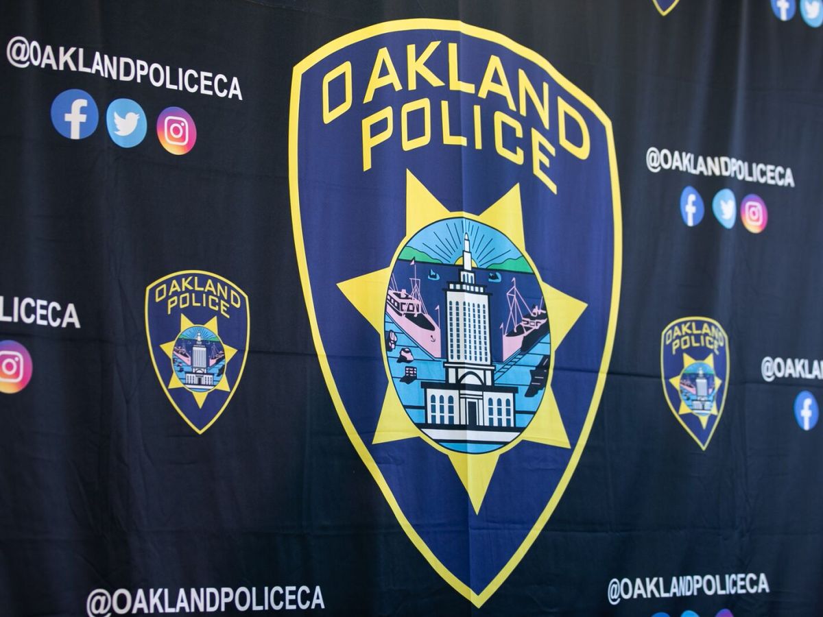 The Oakland Police Department's emblem depicting a badge with a six-pointed star, City Hall, and ships at the port.