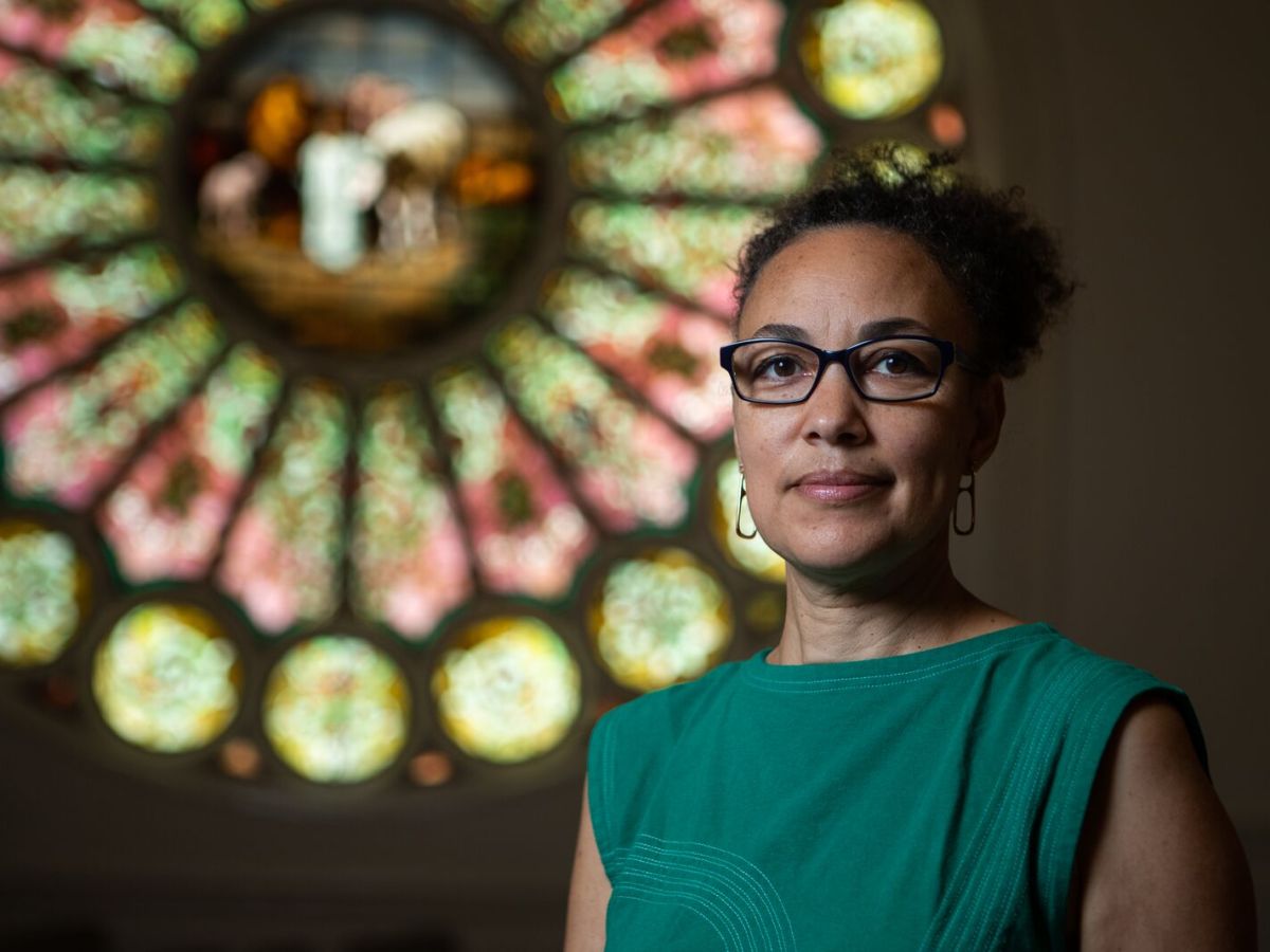 Ariana Makau, founder of Nzilani Glass Conservation, a stained glass preservation company, in front of a recent restoration project at Resurrection Church Oakland.