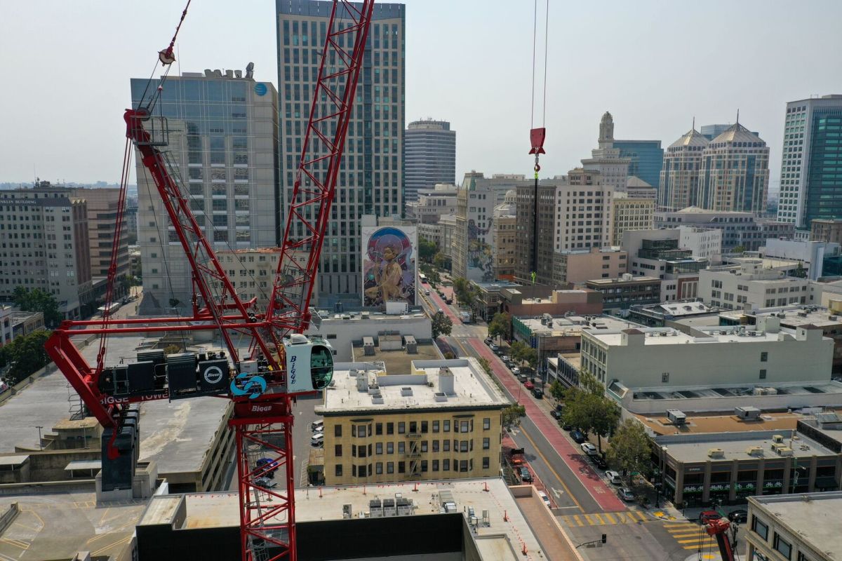 high-up photo of crane in the foreground. city buildings in the background