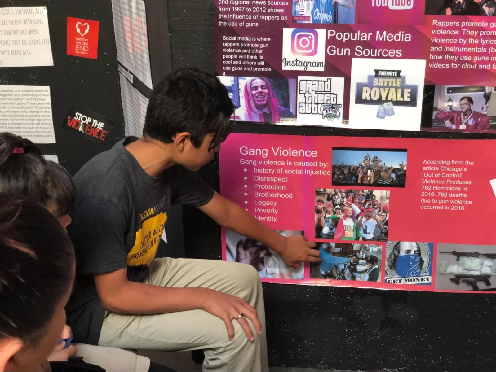 student points to a poster about gang violence