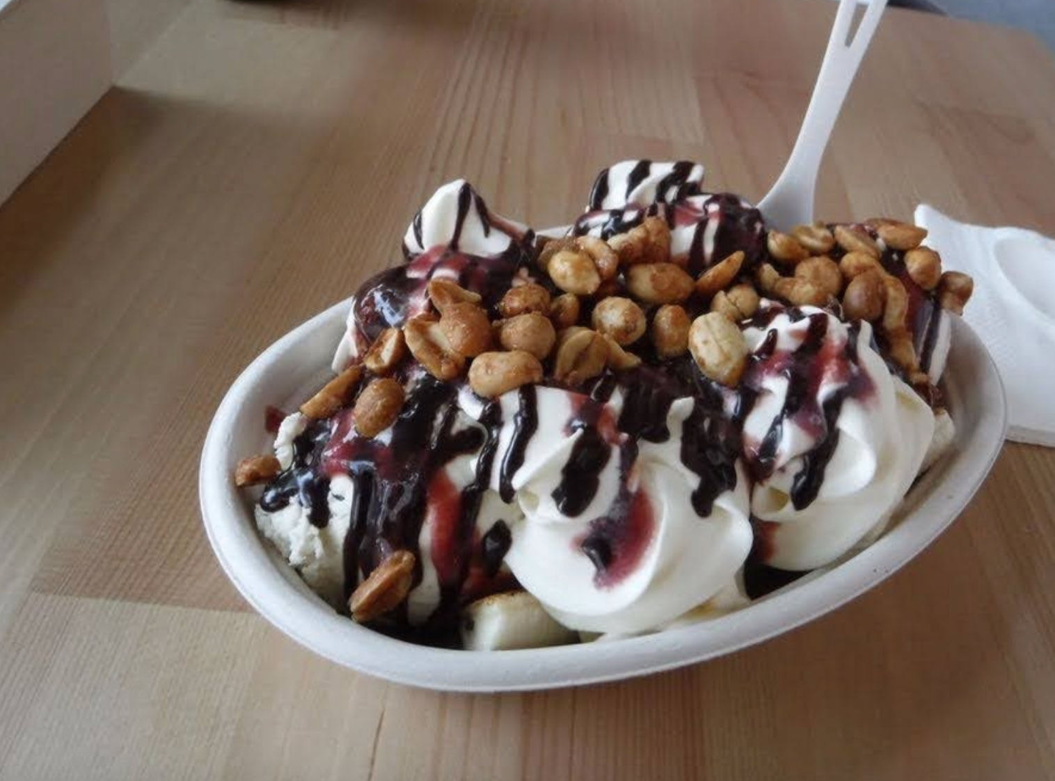 A banana split with chocolate sauce and nuts on top