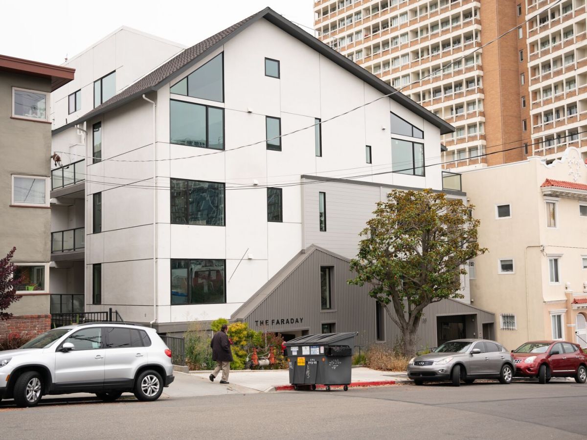 A new-looking mid-size building is nestled between small and large apartment buildings.