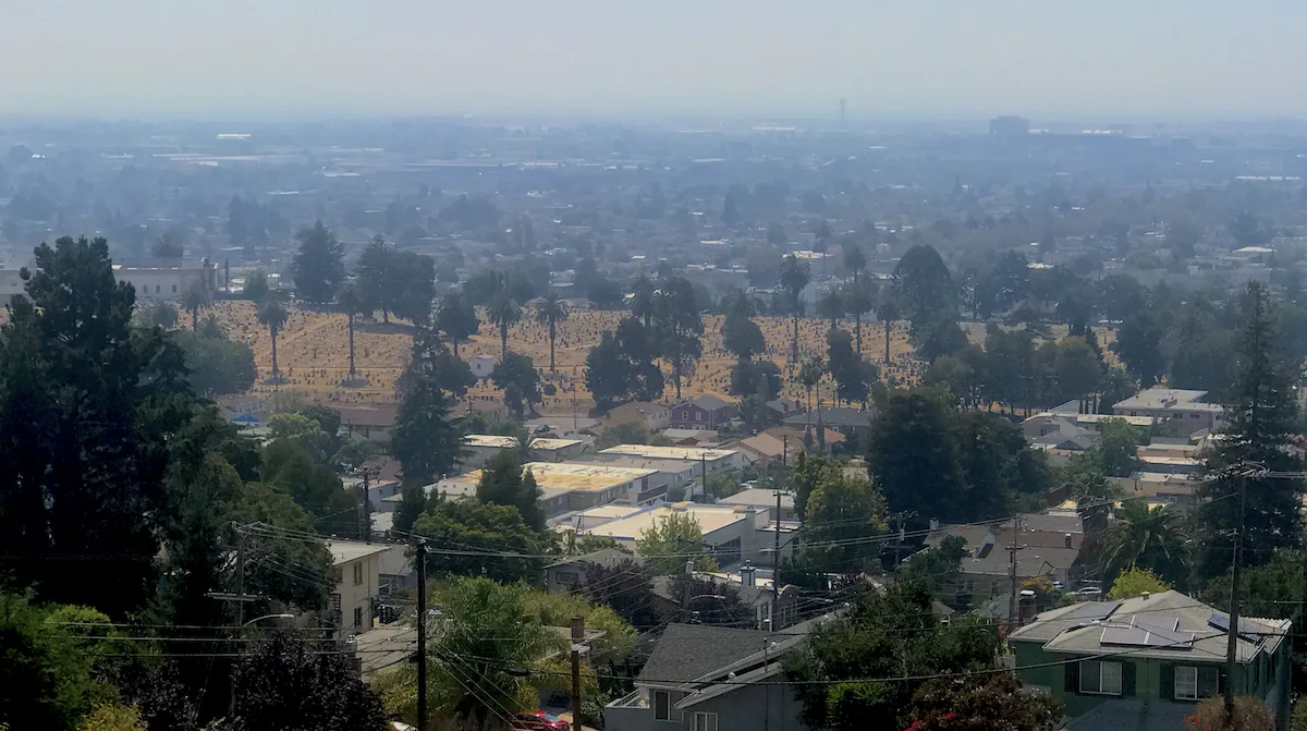 Smokey skies over an expanse of trees and residential neighborhoods, viewed from elevation.
