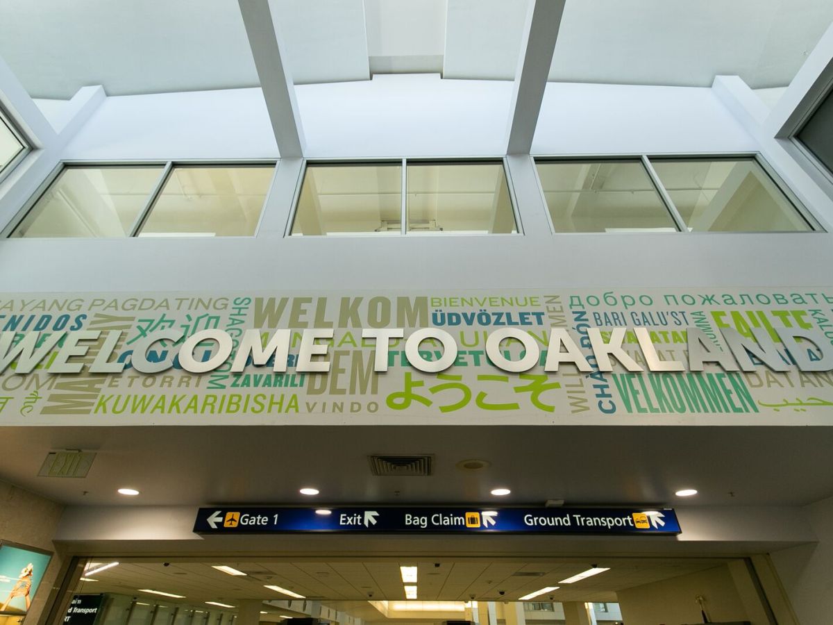 A sign at one of the terminals at Oakland International Airport welcomes travelers in English in silver lettering, and in different colors in different languages.