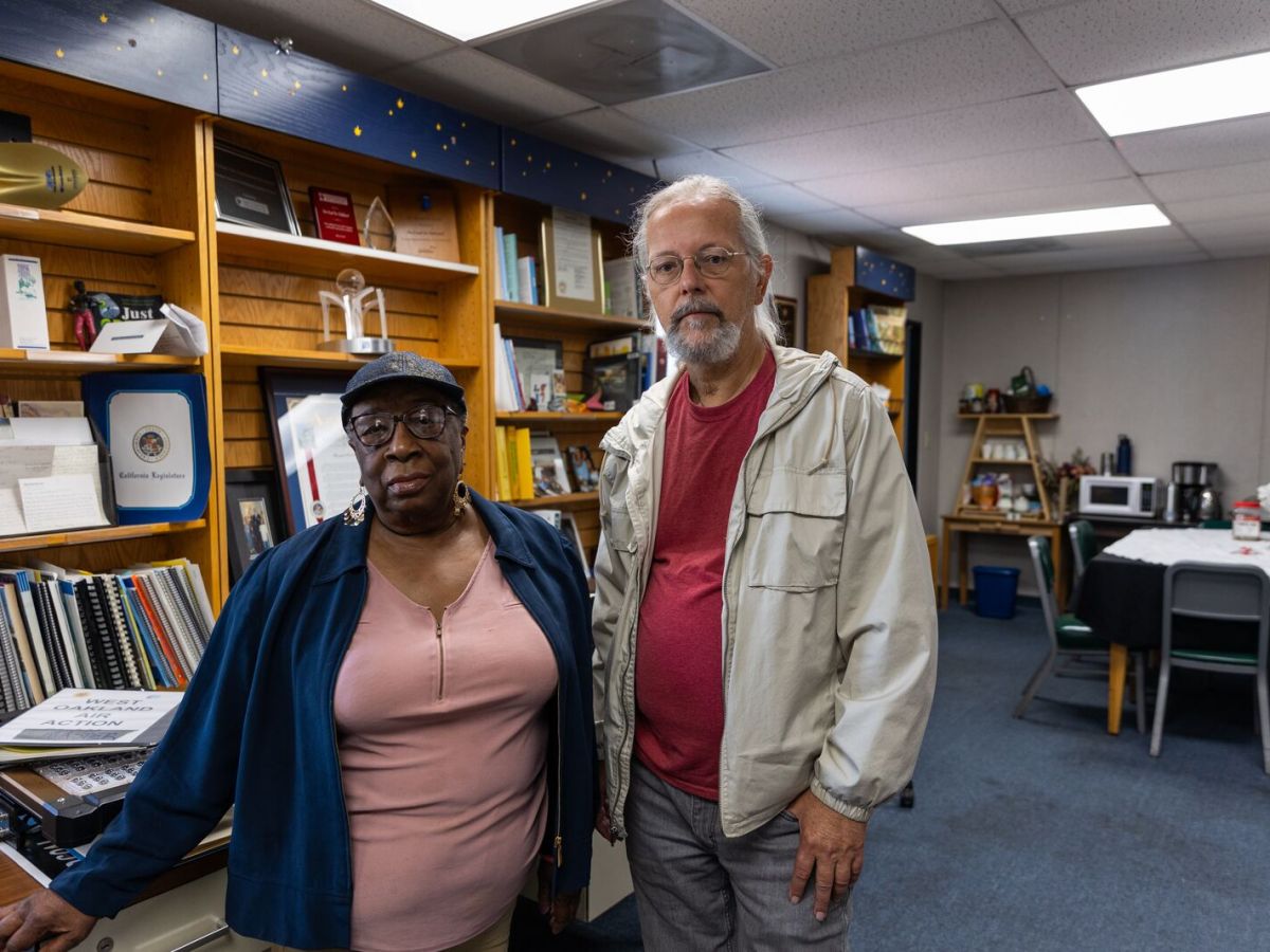 A woman and man stand side by side in front of several book shelves in an office.