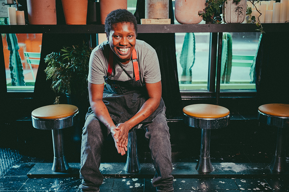 Chef Selasie Dotse sits on a stool in front of a bar.