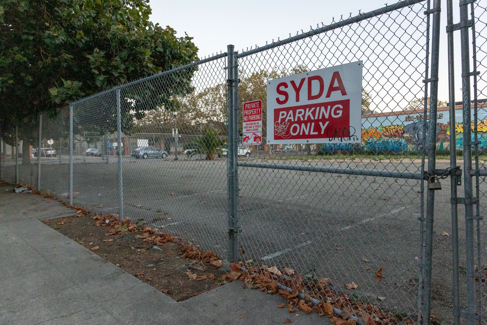 An empty, fenced-off parking lot with a sign that says "SYDA parking only."