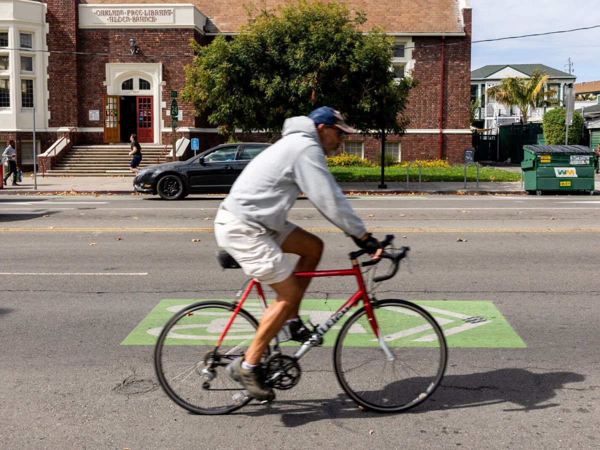 A man rides a bike along a wide street.
