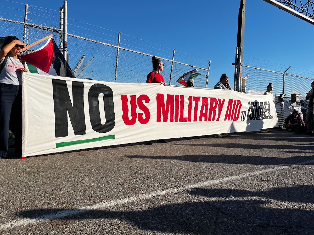 Protesters hold a banner that says "No U.S. military aid to Israel."