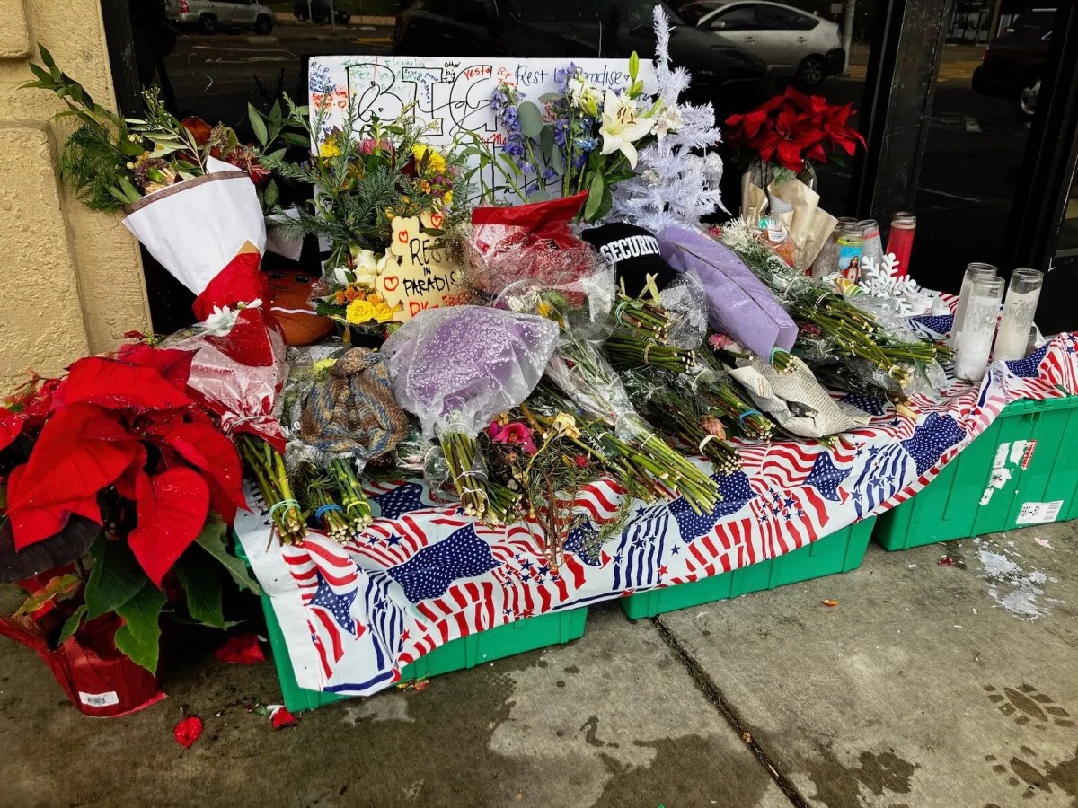 Memorial with flowers and signs on a rainy ground.
