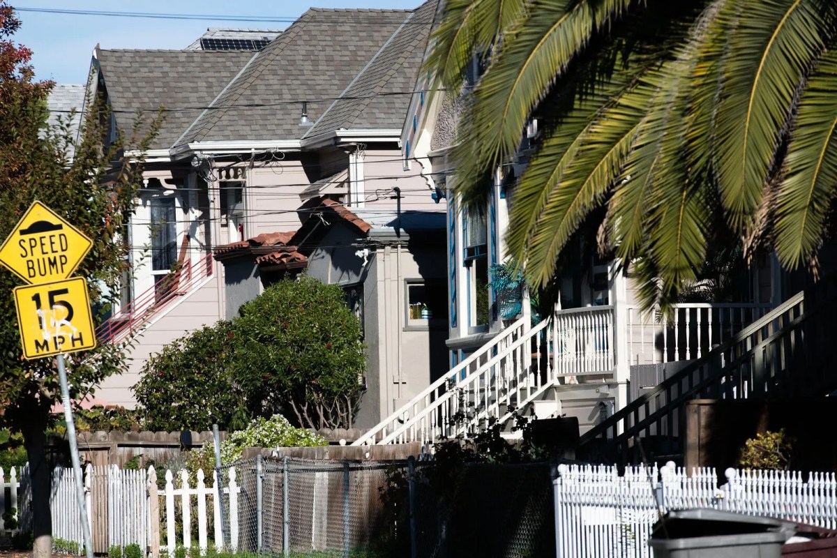 Several small single-family homes next to each other, by palm trees.