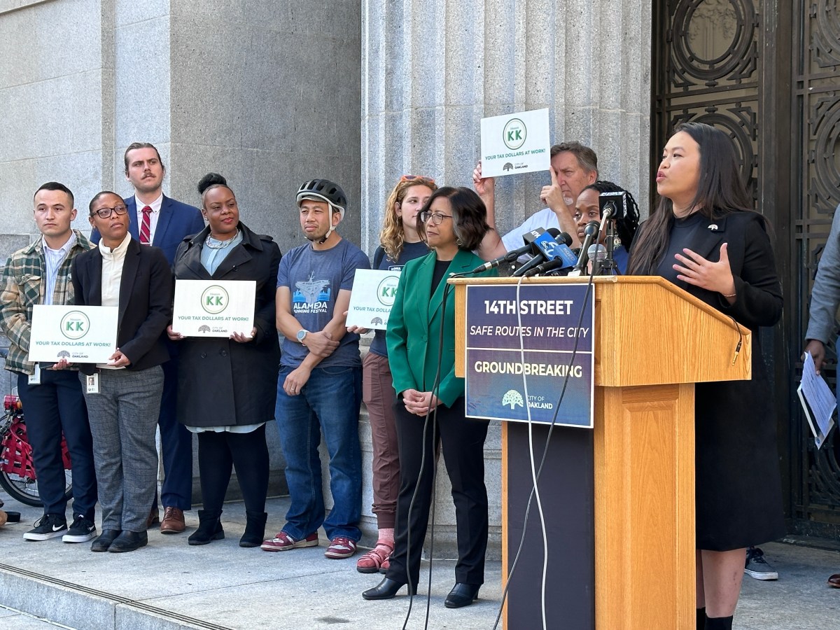 Oakland Mayor Sheng Thao speaks at a podium on the steps of City Hall. Behind her are city councilmembers and traffic safety advocates.