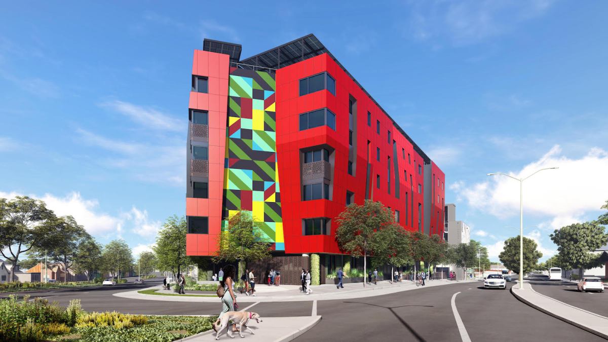 Architectural rendering of a striking red apartment building at a city intersection, with one side decorated with a blocky, colorful design.