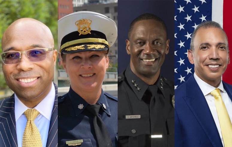 From left to right, a Black man in a suit, a white woman in a police uniform, a Black man in a police uniform, and a Latino man in a suit.